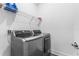Modern side by side washer and dryer with wire rack and tile flooring in laundry room at 14955 Lebeau Loop, Winter Garden, FL 34787