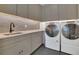 Laundry room with gray cabinets, quartz countertop, dark floors, tile backsplash, and washer and dryer at 15198 E Oakland Ave, Winter Garden, FL 34787