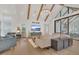 Open floor plan with living room and view into dining room and kitchen, light wood floors and exposed wood beams at 15198 E Oakland Ave, Winter Garden, FL 34787