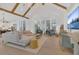 Open floorplan living room with light wood floors, vaulted ceilings, exposed beams, and modern furniture at 15198 E Oakland Ave, Winter Garden, FL 34787