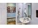 Charming powder room with pedestal sink and framed photos adorning the wall outside at 15510 Lake Burnett Shore Ct, Winter Garden, FL 34787