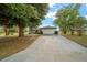 A long driveway leading up to a charming home with a large garage, framed by mature trees at 16190 Sw 16Th Ct, Ocala, FL 34473