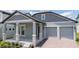 Inviting home featuring light blue exterior, a two-car garage, and covered front porch with stone columns and brick-paved driveway at 16489 Silver Brook Way, Winter Garden, FL 34787