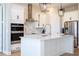 Bright open kitchen featuring stainless steel appliances, white cabinets, island with sink, and modern pendant lights at 16489 Silver Brook Way, Winter Garden, FL 34787