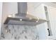 Modern stainless steel kitchen hood and marble patterned backsplash at 16489 Silver Brook Way, Winter Garden, FL 34787