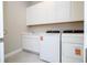 Bright laundry room featuring modern white appliances, sink, and extra storage cabinets at 16489 Silver Brook Way, Winter Garden, FL 34787
