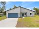 Charming single-story home featuring a modern design, blue garage door, and well-maintained lawn at 2506 Sw 158Th Lane Rd, Ocala, FL 34473
