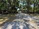 Wide shot of the front of the home, which has a large parking area and green trees at 25824 Shawnee St, Sorrento, FL 32776