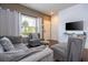 Modern living room featuring stylish gray furniture, a large window with natural light, and a mounted flat-screen TV at 3229 Cupid Pl, Kissimmee, FL 34747