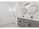 Modern bathroom features dual vanities, gray cabinets, and round mirrors at 441 Caraway Dr, Kissimmee, FL 34759