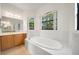 Bright bathroom showcasing a luxurious soaking tub, wooden vanity with sink, and window letting in natural light at 453 Sorrento Rd, Kissimmee, FL 34759