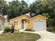 Charming yellow single-story home featuring a one-car garage and gated courtyard at 561 Portland Cir, Apopka, FL 32703