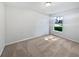 A simple, bright bedroom with neutral carpet and walls, featuring a single window for natural light at 612 Doe Cove Pl, Apopka, FL 32703