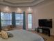 Bright main bedroom with a tray ceiling, carpeted floors, large windows with curtains, and an exterior door at 635 Whitman Cv, Longwood, FL 32750