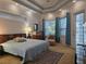Bright main bedroom with a tray ceiling, carpeted floors, large windows with curtains, and an exterior door at 635 Whitman Cv, Longwood, FL 32750