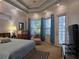Bright main bedroom with a tray ceiling, carpeted floors, large windows with curtains, and an exterior door at 635 Whitman Cv, Longwood, FL 32750