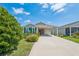 Inviting single-story home with a covered carport, enhanced by verdant landscaping and a well-kept lawn at 747 Louise Ln, The Villages, FL 32163