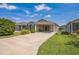 View of the house highlighting the driveway leading to the covered carport, with a well manicured lawn at 747 Louise Ln, The Villages, FL 32163