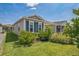 Close up showing the charming single-story home featuring lush landscaping and neutral siding with blue shutters at 747 Louise Ln, The Villages, FL 32163