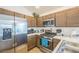 Close-up of modern kitchen showcasing stainless steel appliances, brown cabinets, and a functional layout at 747 Louise Ln, The Villages, FL 32163