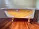 Close-up of bathtub with artistic bird painting and golden claw feet on wooden floor at 748 W Florence Ave, Deland, FL 32720