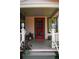 Close-up of the covered front porch of a pink cottage with a red door and potted plants at 748 W Florence Ave, Deland, FL 32720