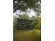 Side view of a backyard outbuilding featuring a dark door and an overhanging tree at 748 W Florence Ave, Deland, FL 32720