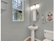 Well-lit powder room featuring a pedestal sink, decorative mirror, and neutral wall color at 8445 Leeland Archer Blvd, Orlando, FL 32836