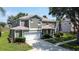 Charming two-story home featuring a two-car garage, lush lawn, and mature trees at 8518 La Isla Dr, Kissimmee, FL 34747