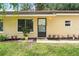 Close-up of home entrance with manicured flowerbeds, small front window and tan exterior at 10849 William Tell Dr, Orlando, FL 32821