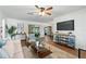 Inviting living room featuring hardwood flooring, modern furniture, ceiling fan, and large tv for entertainment at 10849 William Tell Dr, Orlando, FL 32821