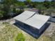 An elevated angle view showcasing the metal roof with light gray siding and lush yard space at 11624 Ocklawaha Dr, Leesburg, FL 34788