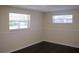 Bedroom featuring two windows for natural light and dark wood flooring at 11624 Ocklawaha Dr, Leesburg, FL 34788