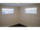 Bedroom featuring two windows for natural light and dark wood flooring at 11624 Ocklawaha Dr, Leesburg, FL 34788