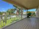 A covered back porch has a wooden deck with plants and a view of the fenced yard with lush tropical landscaping at 1208 Castleport Rd, Winter Garden, FL 34787