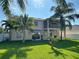 A big backyard is surrounded by a white fence and has a grass lawn, palm trees, and the back of the house at 1208 Castleport Rd, Winter Garden, FL 34787