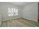A bedroom features neutral walls, baseboards, a window with shutters, and gray wood-look floors at 1208 Castleport Rd, Winter Garden, FL 34787