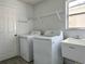 A bright laundry room has appliances, a utility sink, metal shelving, and a window for natural light at 1208 Castleport Rd, Winter Garden, FL 34787
