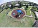 Aerial view of a colorful, fenced playground with various play structures, set in a lush, green lawn at 1208 Castleport Rd, Winter Garden, FL 34787