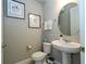Stylish half bathroom featuring a pedestal sink, round mirror, and modern decor at 12259 Bracco St, Winter Garden, FL 34787