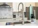 Close-up of a stainless steel kitchen sink with a pull-down faucet and white quartz countertops at 12259 Bracco St, Winter Garden, FL 34787