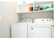 Well-organized laundry room featuring a white washer and dryer with ample shelving for storage at 12259 Bracco St, Winter Garden, FL 34787