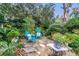 Charming stone patio surrounded by lush landscaping and mature trees, featuring turquoise Adirondack chairs at 1315 E 24Th St, Sanford, FL 32771