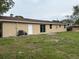 A backyard features a tan-colored house with sliding glass doors and a white door, complemented by sparse green grass at 1516 Culverhouse Dr, Daytona Beach, FL 32117