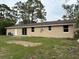 A backyard features a tan-colored house with sliding glass doors and a white door, complemented by sparse green grass at 1516 Culverhouse Dr, Daytona Beach, FL 32117