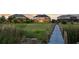 Backyard view of a lake, dock, grass, and houses at sunset at 16086 Johns Lake Overlook Dr, Winter Garden, FL 34787