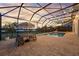 Enclosed pool area featuring string lights, table, and patio, with lake views at 16086 Johns Lake Overlook Dr, Winter Garden, FL 34787
