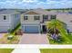 Beautiful two-story home featuring a brick driveway, two-car garage, lush lawn and mature palm tree at 2227 Blue Salvia St, Clermont, FL 34711