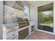 Built in outdoor kitchen with stainless steel grill, stone backsplash, and granite countertop at 2227 Blue Salvia St, Clermont, FL 34711