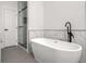 Contemporary bathroom with a soaking tub and walk-in shower with glass door, complemented by grey tile at 309 N Kepler Rd, Deland, FL 32724